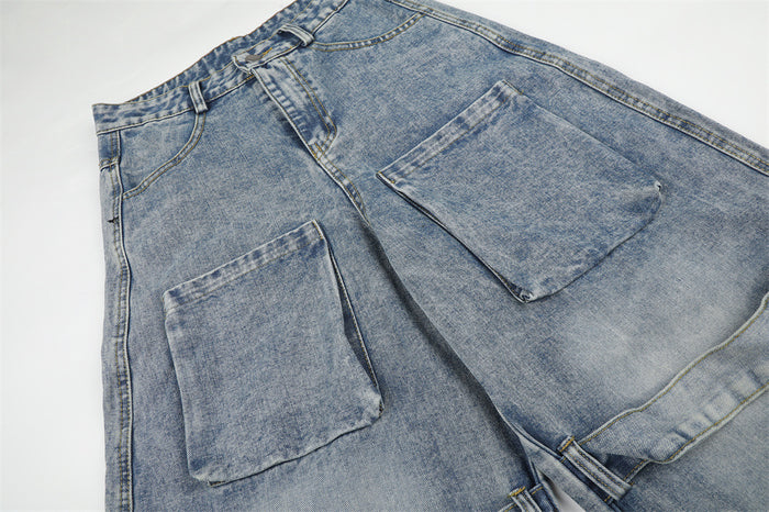 Close-up of washed blue denim cargo jeans showing front and thigh patch pockets with stitched edges