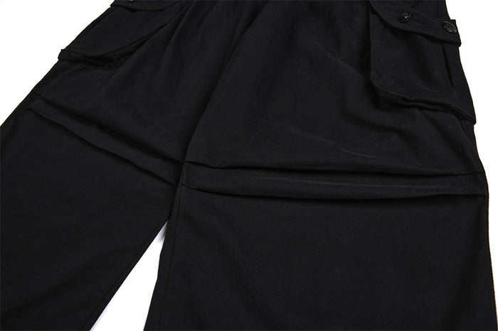 Close-up of black cargo pants showing the layered knee panel and flap pocket construction