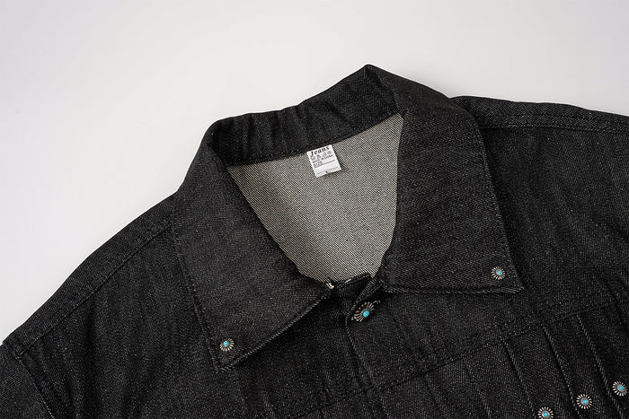 Close-up of the black denim jacket collar, upper front, metal snap details, and turquoise stud accents