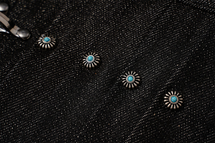 Detailed view of turquoise-centered silver-toned studs arranged across the black denim jacket front
