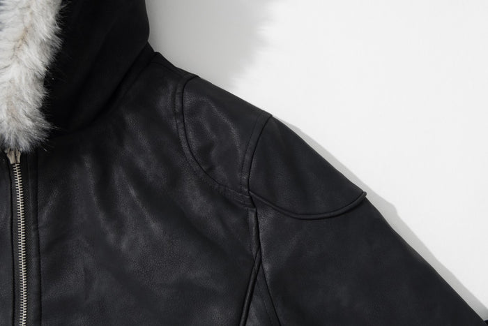 Close-up of the black faux leather jacket shoulder showing curved stitched panel detailing and hood trim