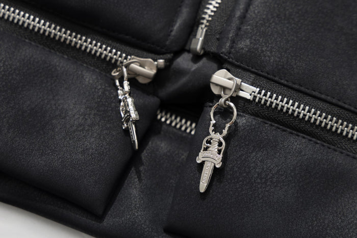 Close-up of the jacket front showing twin silver zippers with decorative metal pull charms on black faux leather