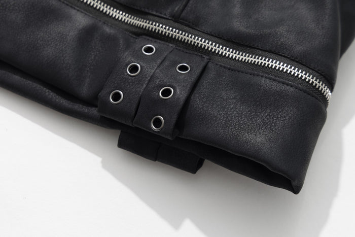 Close-up of the jacket hem showing a silver zipper, black faux leather tabs, and metal eyelets