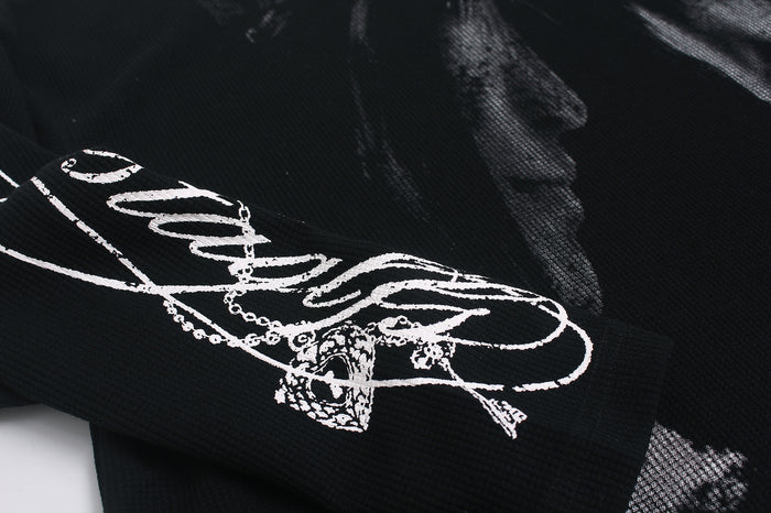 Close-up of the black sleeve featuring a bold white cursive graphic with layered linework and ornamental detail