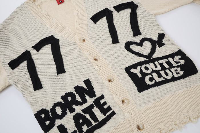 Cream cardigan front close-up showing black 77 graphics, Born Late text, heart motif, and Youths Club patch