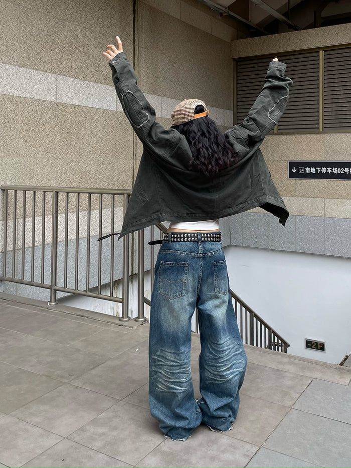 Back view of a model wearing a dark army green jacket with arms raised, showing its short boxy fit