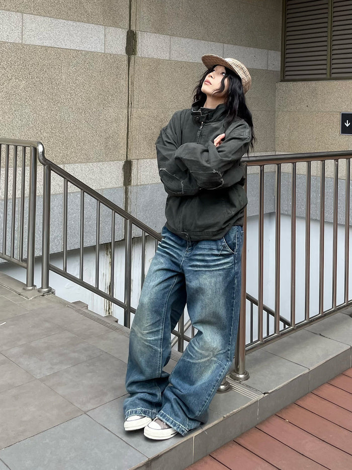 Full-length model view wearing a dark army green Harrington jacket with a distressed collar and blue jeans