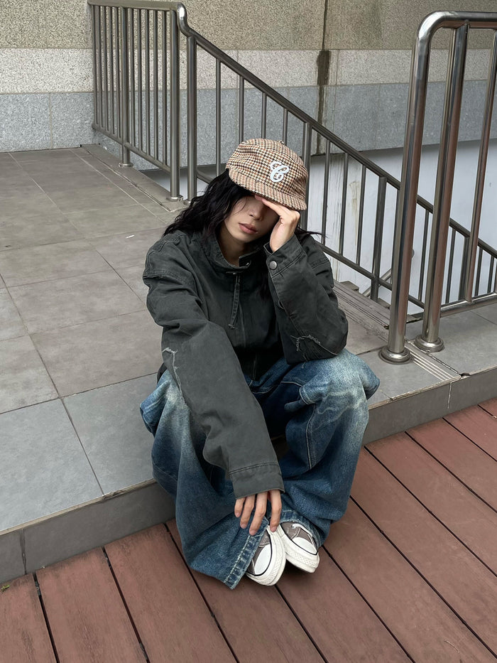 Seated model wearing a dark army green jacket, showing the long sleeves and distressed collar detail