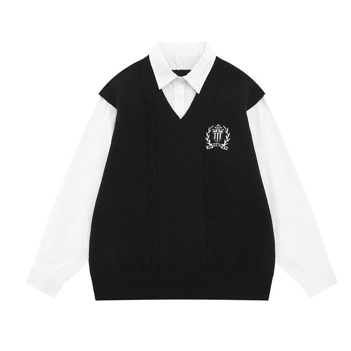 Front view of a black cable-knit sweater vest layered over a white collared shirt with crest embroidery
