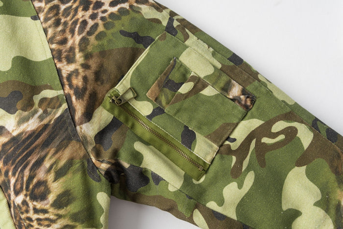 Close-up of the camouflage sleeve showing a rectangular flap pocket with a zipper opening