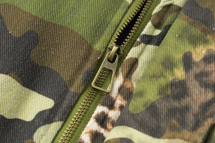 Close-up of the metal front zipper and pull against the jacket's camouflage and leopard-print fabric