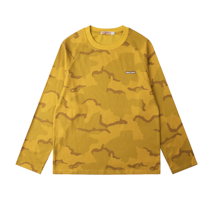 Front view of a mustard yellow waffle-knit shirt with brown camouflage shapes and a small chest label