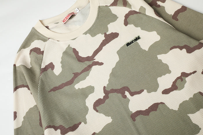 Close-up of the cream camouflage shirt showing its waffle-knit texture, ribbed collar, and small chest label