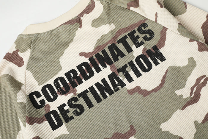 Close-up of black Coordinates Destination lettering printed across the cream camouflage waffle-knit shirt