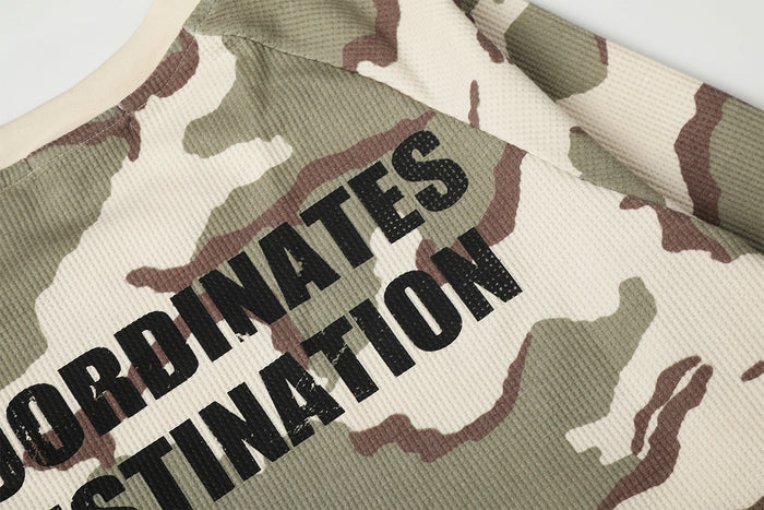 Detailed view of bold black Coordinates Destination text over the cream, sage, and brown camouflage pattern