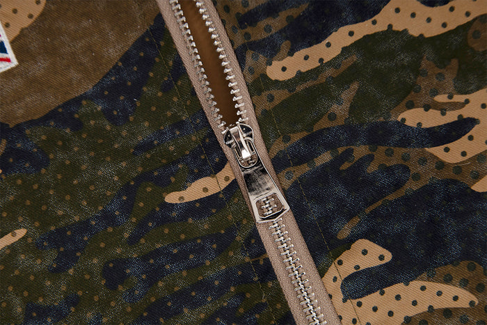 Close-up of the silver two-way zipper against the jacket's brown, olive, and navy camouflage fabric