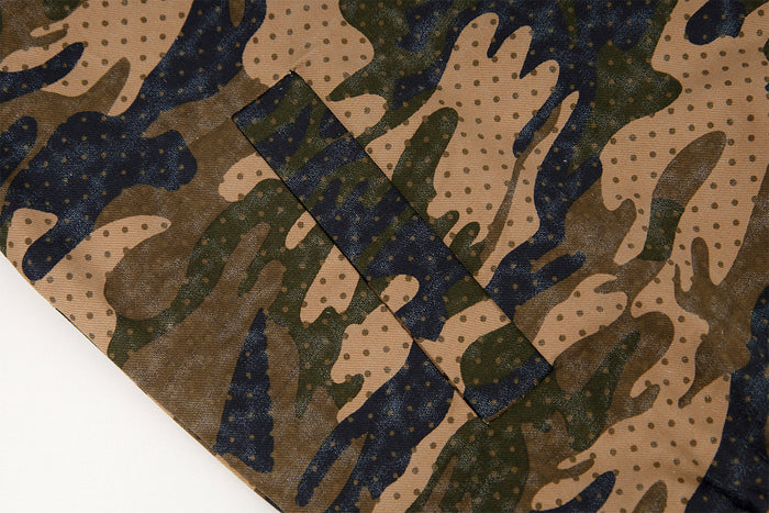 Close-up of a rectangular stitched fabric tab on the jacket's brown and navy camouflage material