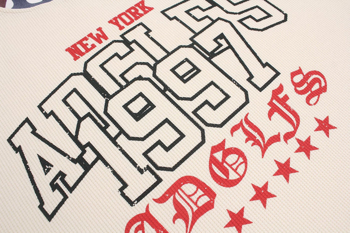 Close-up of the cream waffle-knit front showing the outlined New York 1997 graphic in black and red