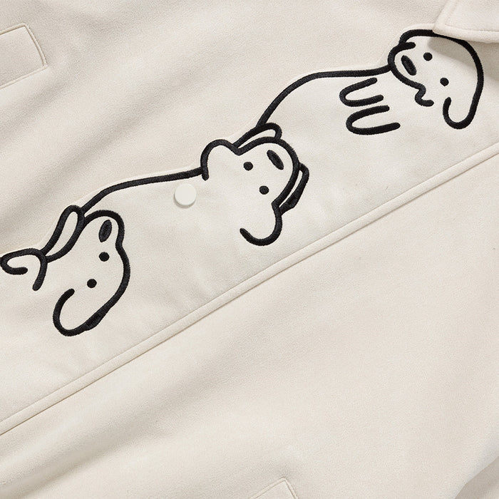 Detailed view of three stacked black cartoon dog figures embroidered along the cream jacket front