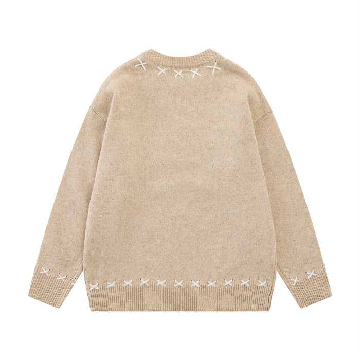 Beige knit sweater back with white X-shaped stitching around the collar, cuffs, and lower hem