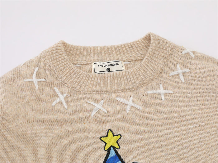 Close-up of the beige sweater neckline showing ribbed knit trim, white X stitching, and the top of the sheep graphic