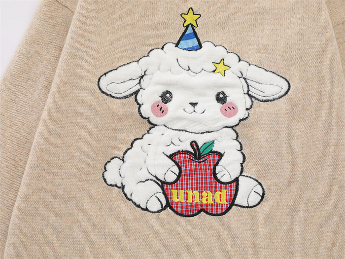 Close-up of the sweater graphic showing a fluffy cartoon sheep in a party hat holding a red plaid apple