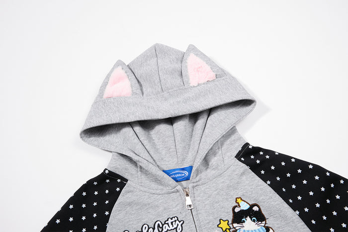Close-up of gray cat-ear hood with pink inner ears, black star-print sleeves, and front cat graphic