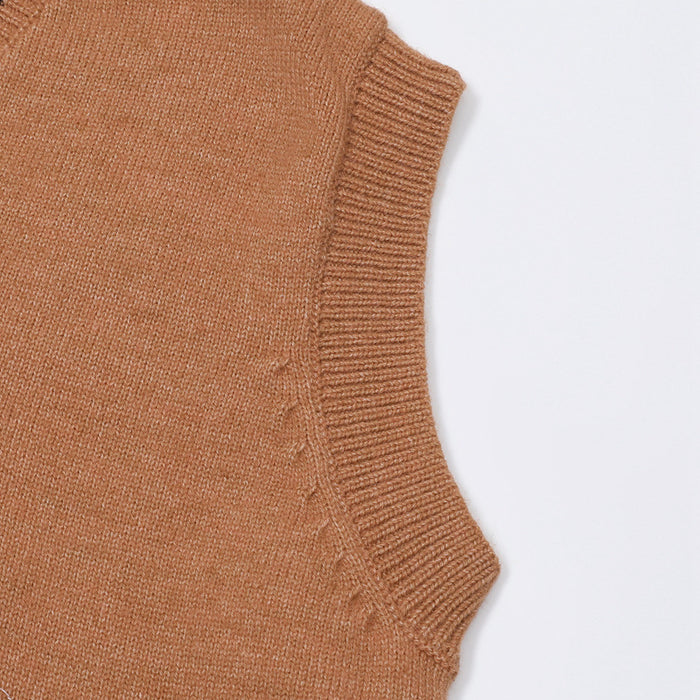 Close-up of the brown knit vest armhole showing its ribbed sleeveless edging and fine knit texture