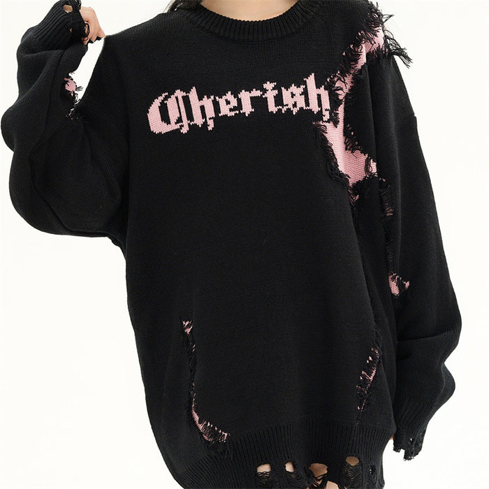 Model wearing a black oversized knit sweater with pink distressed patches, gothic chest lettering and frayed hem