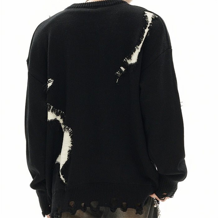 Back view of a black oversized knit sweater with white distressed patches and a scalloped frayed hem
