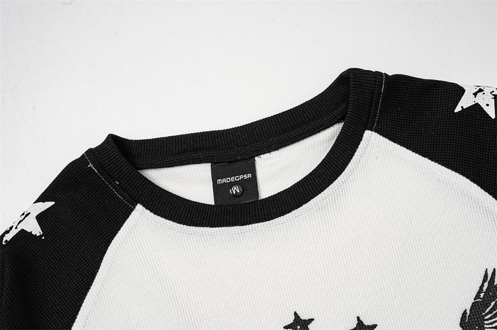 Close-up of the white and black tee showing its ribbed black crew neckline and raglan shoulder seams
