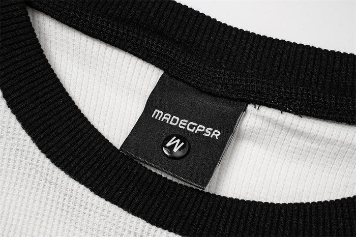 Close-up of the ribbed black crew collar and sewn brand label inside the white raglan tee