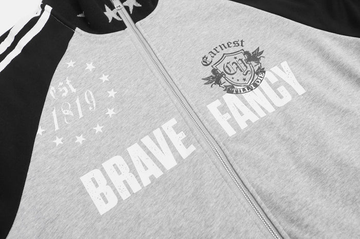 Close-up of the gray jacket front with white BRAVE and FANCY graphics, crest, and star motif