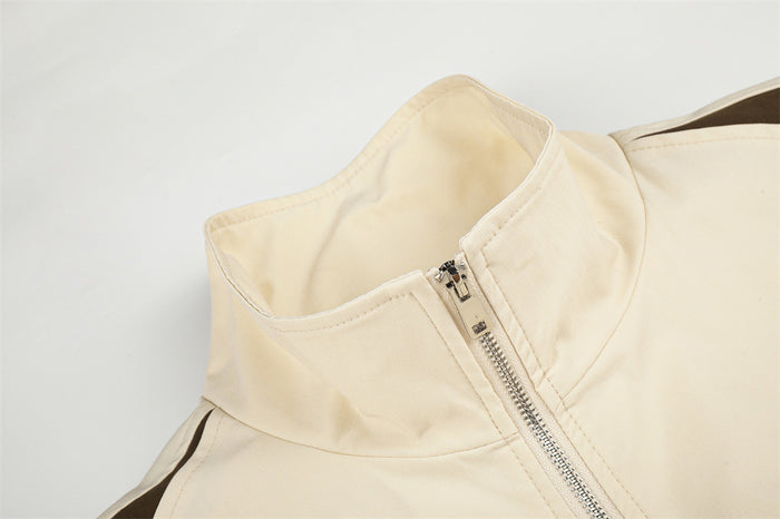 Close-up of the cream jacket's stand collar and silver front zipper with brown shoulder panel detail