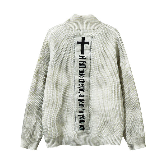 Cream rib-knit cardigan shown from the back with a centered vertical panel featuring a black cross and text