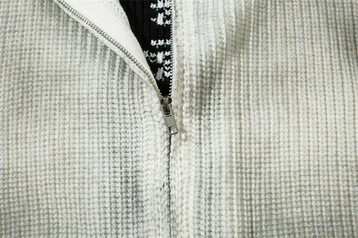 Close-up of the cream cardigan's partially opened metal zipper and textured rib-knit fabric