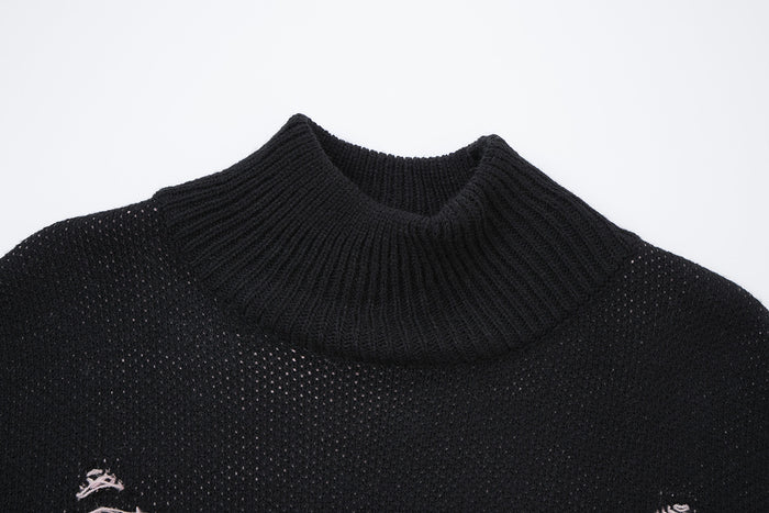 Close-up of the black sweater's ribbed turtleneck collar and open knit texture