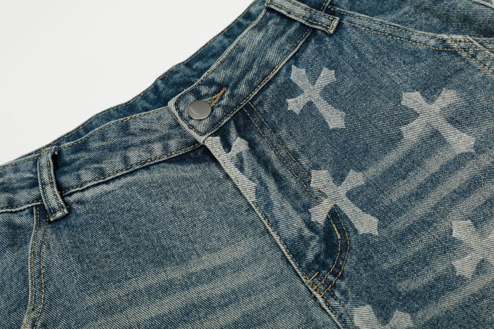 Detailed view of the blue jeans front waist with button, belt loop, seam stitching, and cross-print pattern