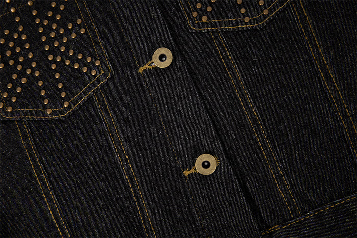 Detailed view of the dark denim jacket front with gold buttons, contrast stitching, and studded pockets