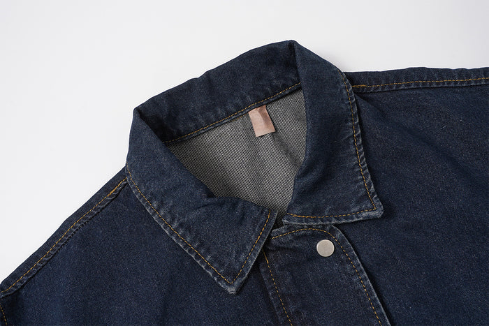Close-up of the dark indigo denim jacket collar showing contrast stitching, inner neck label and front seam