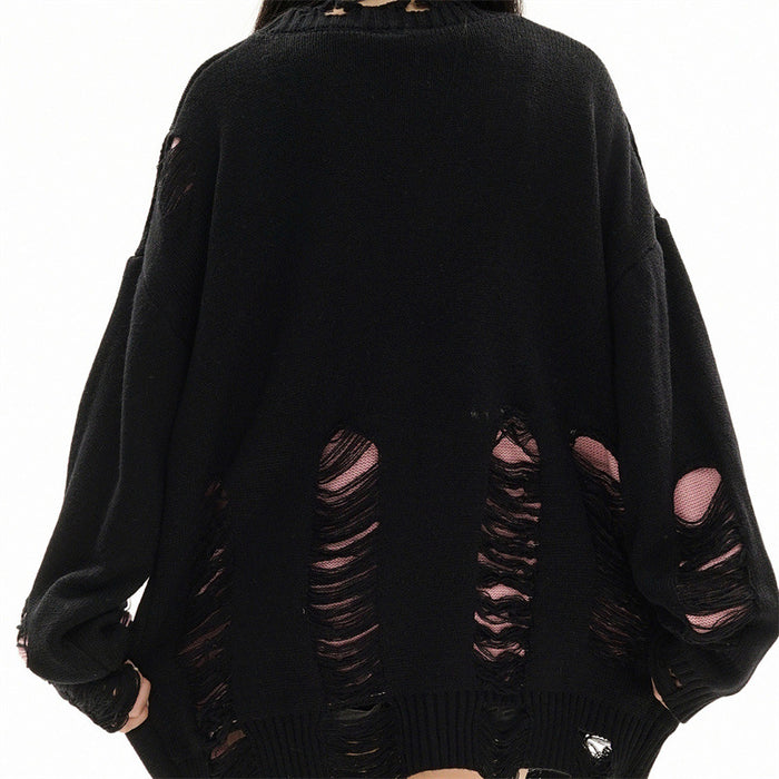 Back view of an oversized black knit cardigan with rows of large distressed tears revealing pink underneath