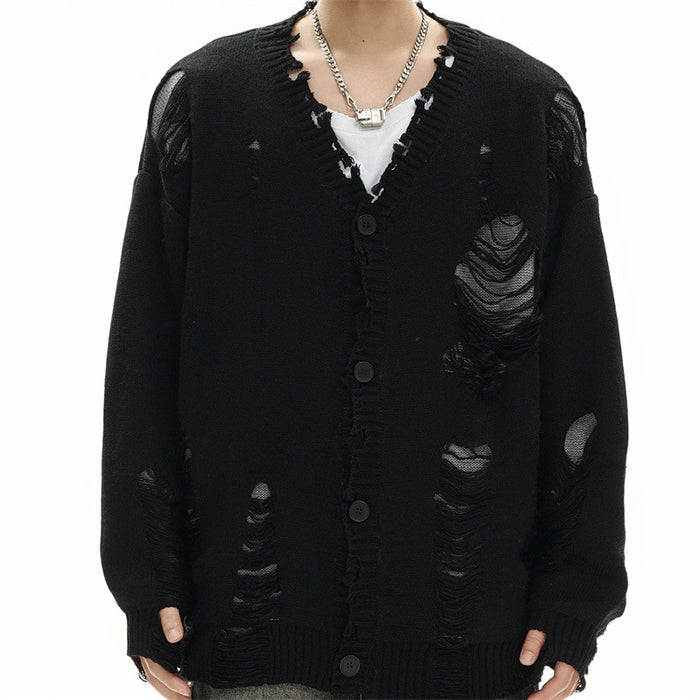 Model wearing a black distressed knit cardigan with V-neck, button front, ripped panels, and white shirt underneath