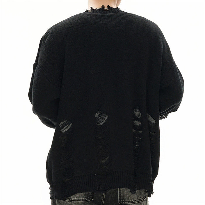 Back view of a model wearing an oversized black knit cardigan with distressed openings near the lower back