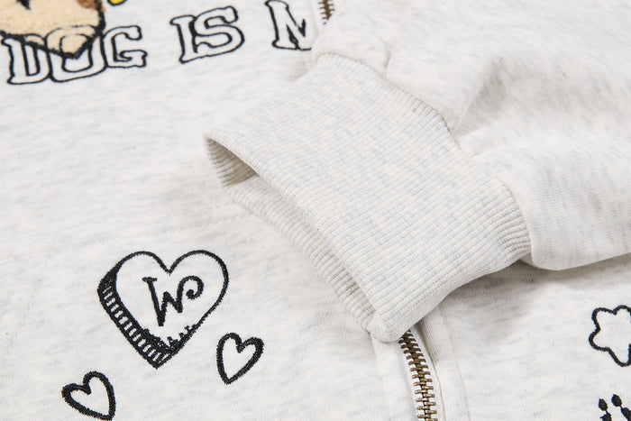 Close-up of a ribbed sleeve cuff, metal zipper, and black heart embroidery on the light gray hoodie