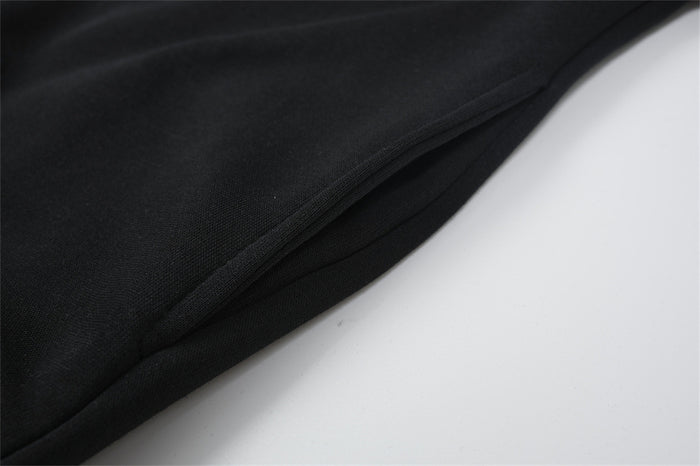 Close-up of black hoodie fabric folded along a stitched edge, showing the smooth surface and seam