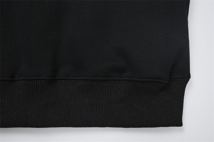 Close-up of the black hoodie bottom hem with a wide ribbed knit band and stitched seam