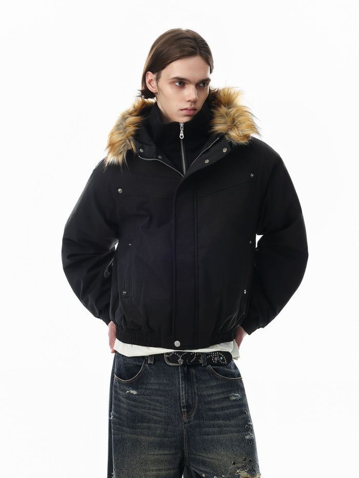 Model wearing a black padded bomber jacket with a tan fur-trimmed hood, front three-quarter view