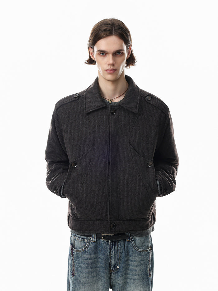 Model wearing a dark brown quilted bomber jacket with a folded collar, front closure, and side pockets