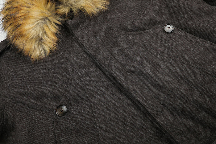 Close-up of the dark brown jacket front showing textured fabric, curved pocket seams, and buttons