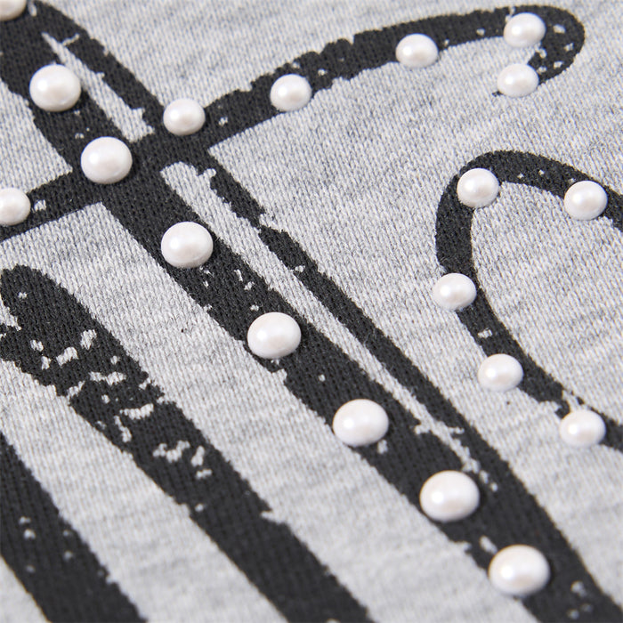 Close-up of black script lettering on gray fabric decorated with small white bead accents